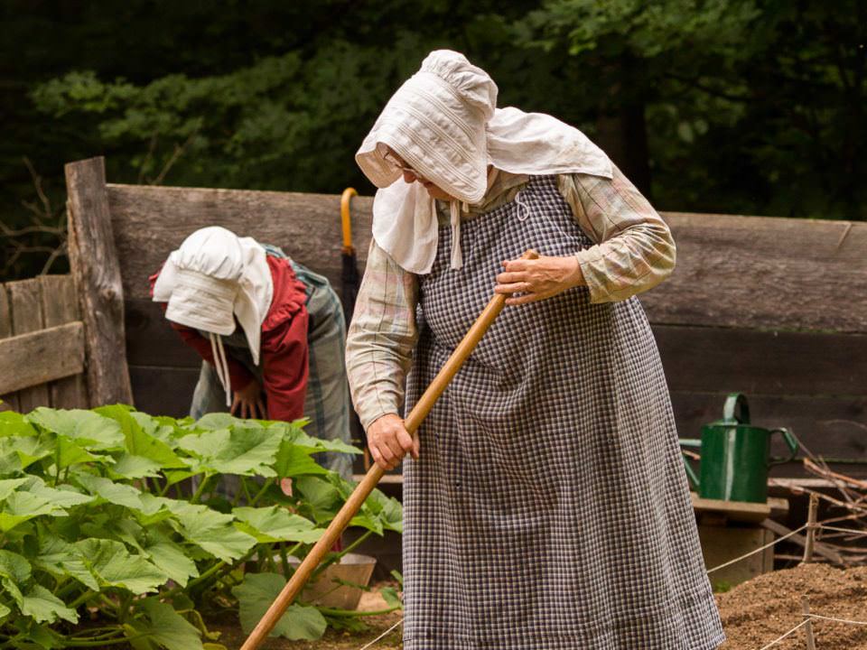 2 costumed historians work in the garden