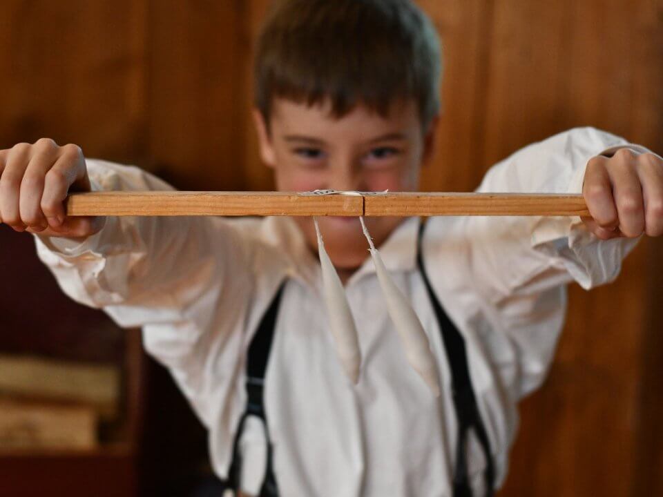 A young boy shows off two candles in progress