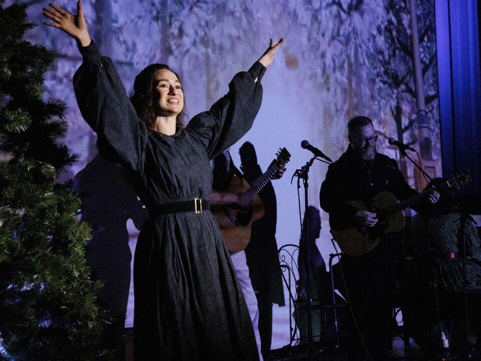 A woman in 1830s attire speaks from a stage