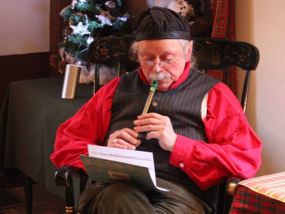 A costumed historian plays some traditional Christmas tunes