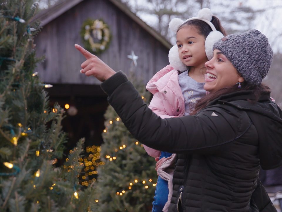 A mom and child look at lit trees outside
