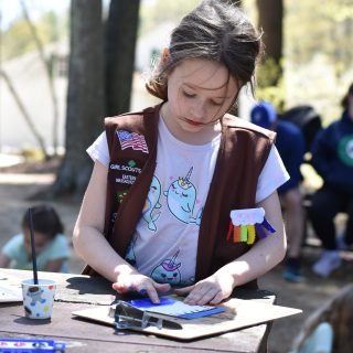 A girl scout paints outside