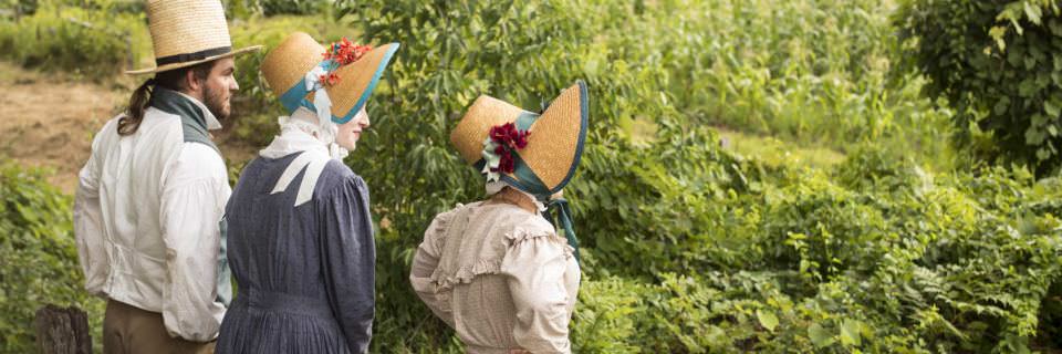 3 individuals dressed in early 19th-century costume outside at Old Sturbridge Village