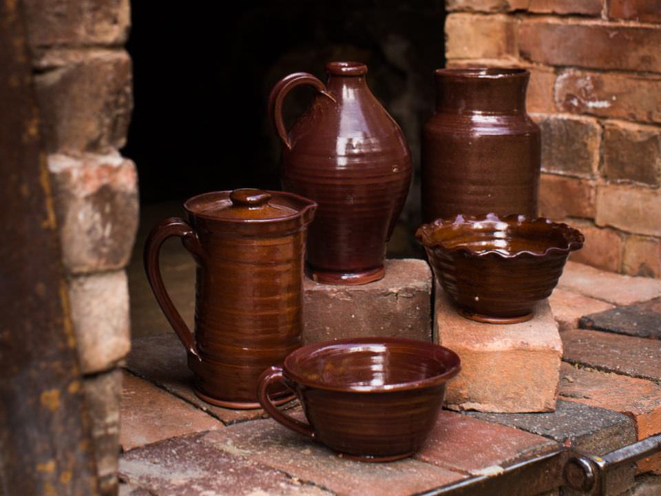 Village-made redware includes mugs, ruffled dishes, covered bean pots, platters and pitchers