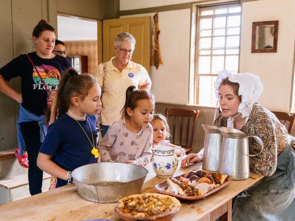Visitors chat with a costumed historian about hearth cooked food