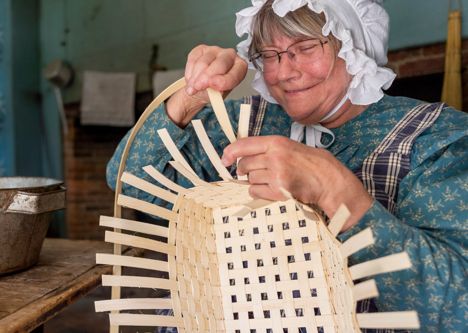 Women in 1830s dress making a basket.